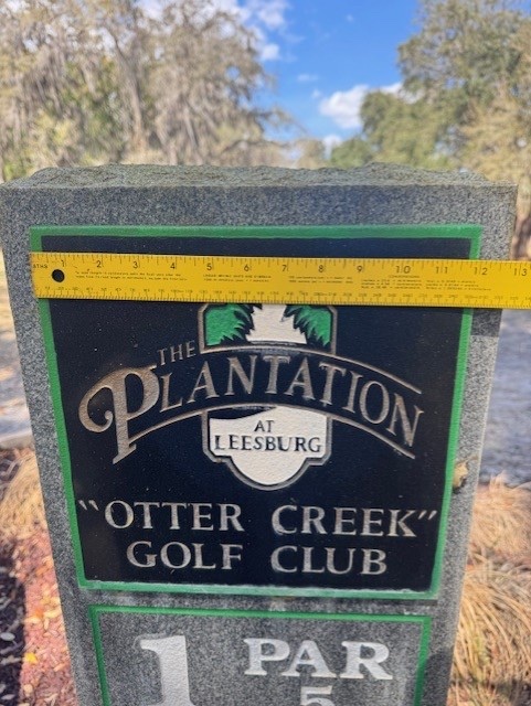 A wider on-site measurement photo of The Plantation at Leesburg monument, tape measure held against the engraved plaque to confirm insert dimensions before fabrication.